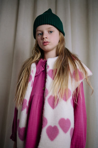 Witte teddy bodywarmer voor meisjes van Daily Brat met roze hartjes, ideaal om te dragen over jurkjes of truien. | Ontdek Daily Brat bij Little Fashion Addict