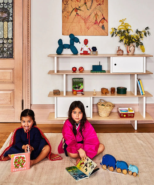 Twee kinderen met boeken voor de Oeuf NYC Mini Library boekenkast in wit en berken