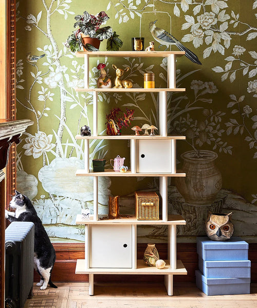 Oeuf NYC Vertical Mini Library met planten en decoratie tegen groen bloemenbehang in een woonkamer