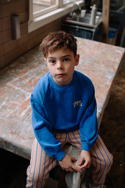 Kind draagt de sportieve sweater in helder kobaltblauw met SPRT&-logo uit de Club Chaos collectie van Sproet & Sprout.