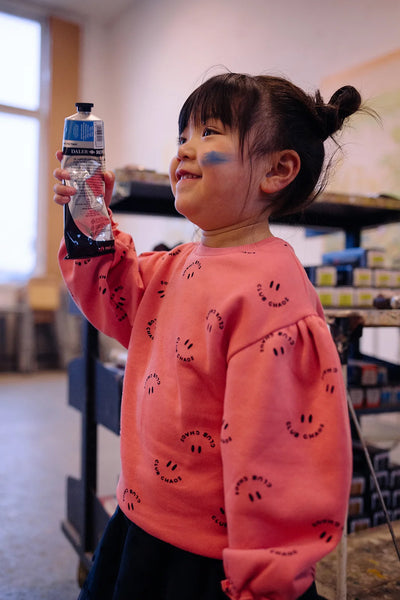 Meisje draagt de warmroze Club Chaos sweater met all-over print uit de Club Chaos collectie van Sproet & Sprout.