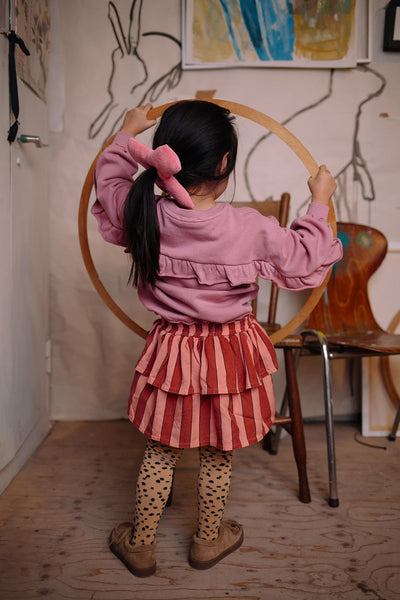 Meisje draagt de zacht oudroze sweater met ruffles op de rug uit de Club Chaos collectie van Sproet & Sprout.