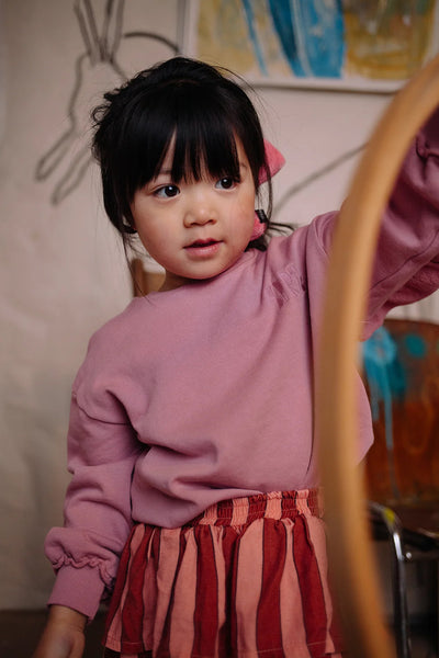 Meisje draagt de zacht oudroze sweater met ruffles op de rug uit de Club Chaos collectie van Sproet & Sprout.