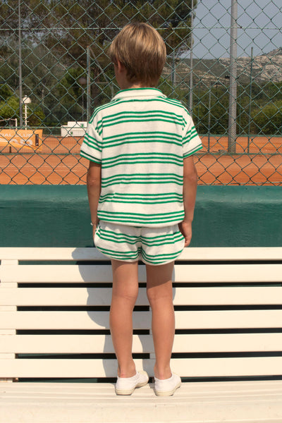 We Are Kids Witte Polo met korte mouwen en groene strepen, gemaakt van zachte 100% biologisch katoenen terry-stof. Voor jongens en meisjes vanaf 4 jaar. Verkrijgbaar bij Littlefashionaddict.