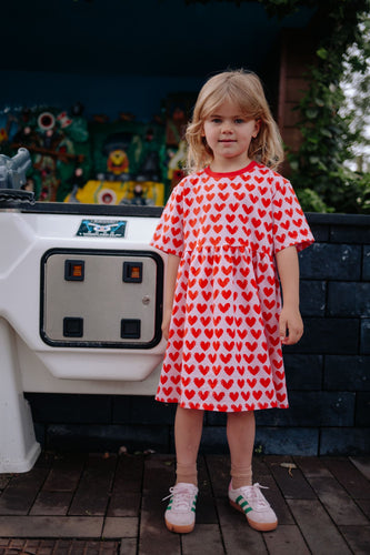 Meisje draagt lichtroze Daily Brat jurk met hartjesprint | Ontdek Daily Brat bij Little Fashion Addict