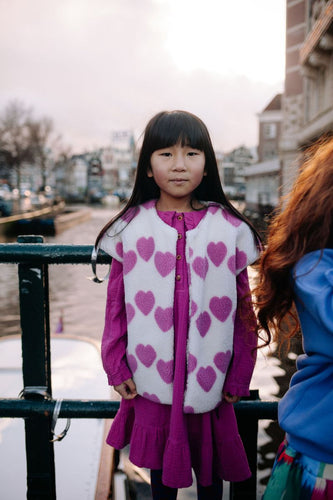 Witte teddy bodywarmer voor meisjes van Daily Brat met roze hartjes, ideaal om te dragen over jurkjes of truien. | Ontdek Daily Brat bij Little Fashion Addict