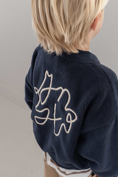 Jenest Jimmy Cardigan Navy Blue – donkerblauwe teddy cardigan met grote ecru borduring op de rug | Verkrijgbaar bij Little Fashion Addict