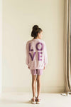 Lichtroze sweater voor meisjes van Jenest met ballonmouwen en op de voorkant een klein paars hartje. De sweater heeft op de achterkant een paarse LOVE-print. | verkrijgbaar bij Little Fashion Addict