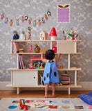 Kind bij de Oeuf NYC Mini Library in wit en berken, gevuld met boeken en speelgoed in een kinderkamer