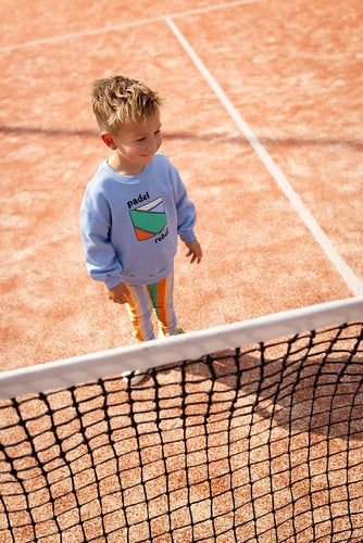 Jong kind draagt blauwe Padel Rebel sweater van Sproet & Sprout op sportveld | Sweatshirt Padel Rebel Forever Blue uit de Champions League of Fun Collectie