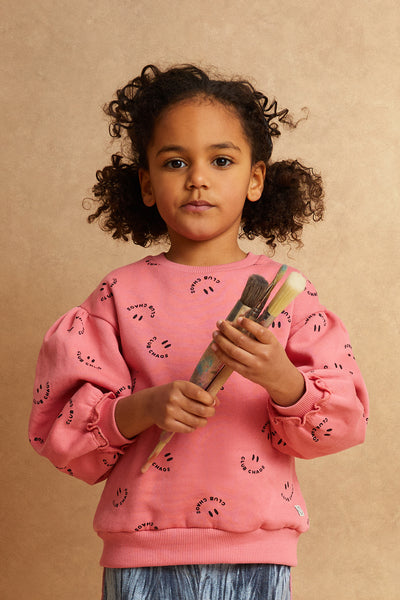 Meisje draagt de warmroze Club Chaos sweater met all-over print uit de Club Chaos collectie van Sproet & Sprout.