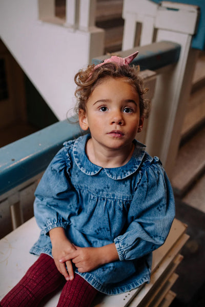 Kind draagt de denim jurk met Club Chaos-print uit de Club Chaos collectie van Sproet & Sprout.