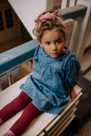 Kind draagt de denim jurk met Club Chaos-print uit de Club Chaos collectie van Sproet & Sprout.