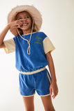 Little Fashion Addict - Maison Tadaboum – Valenia Jumpsuit - Voor meisjes - Korte blauwe jumpsuit in badstof met korte witte mouwen - Meisjesmode - Collectie: Bistrot Tadaboum - verkrijgbaar bij Littlefashionaddict.com